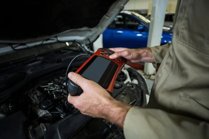 Mechanic using a diagnostic scan tool on a vehicle engine